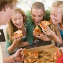 five people eating pizza