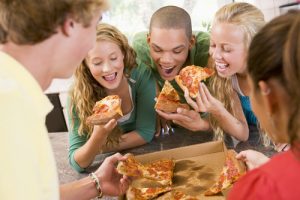 five people eating pizza