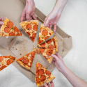 Hands grabbing pizza slices from the box