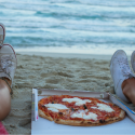 two girls eating pizza by the beach
