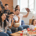 Men and women watching football with pizza